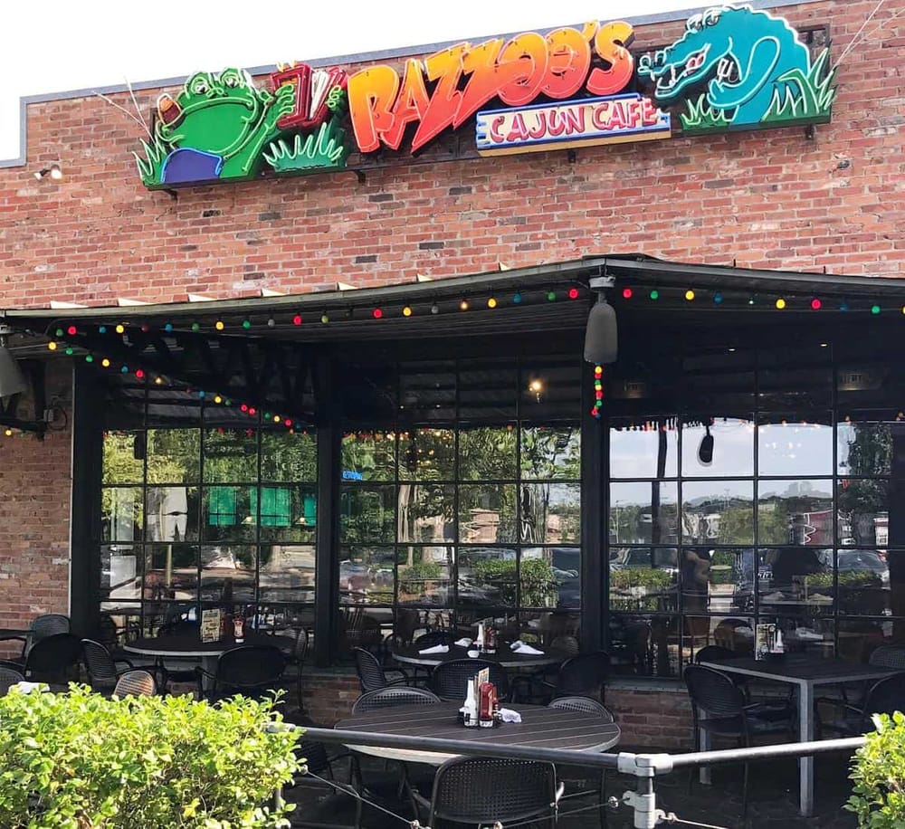 Colorful neon sign for Rayzoo's Cajun Cafe, vibrant outdoor patio with string lights, cozy dining area for delicious Cajun cuisine.