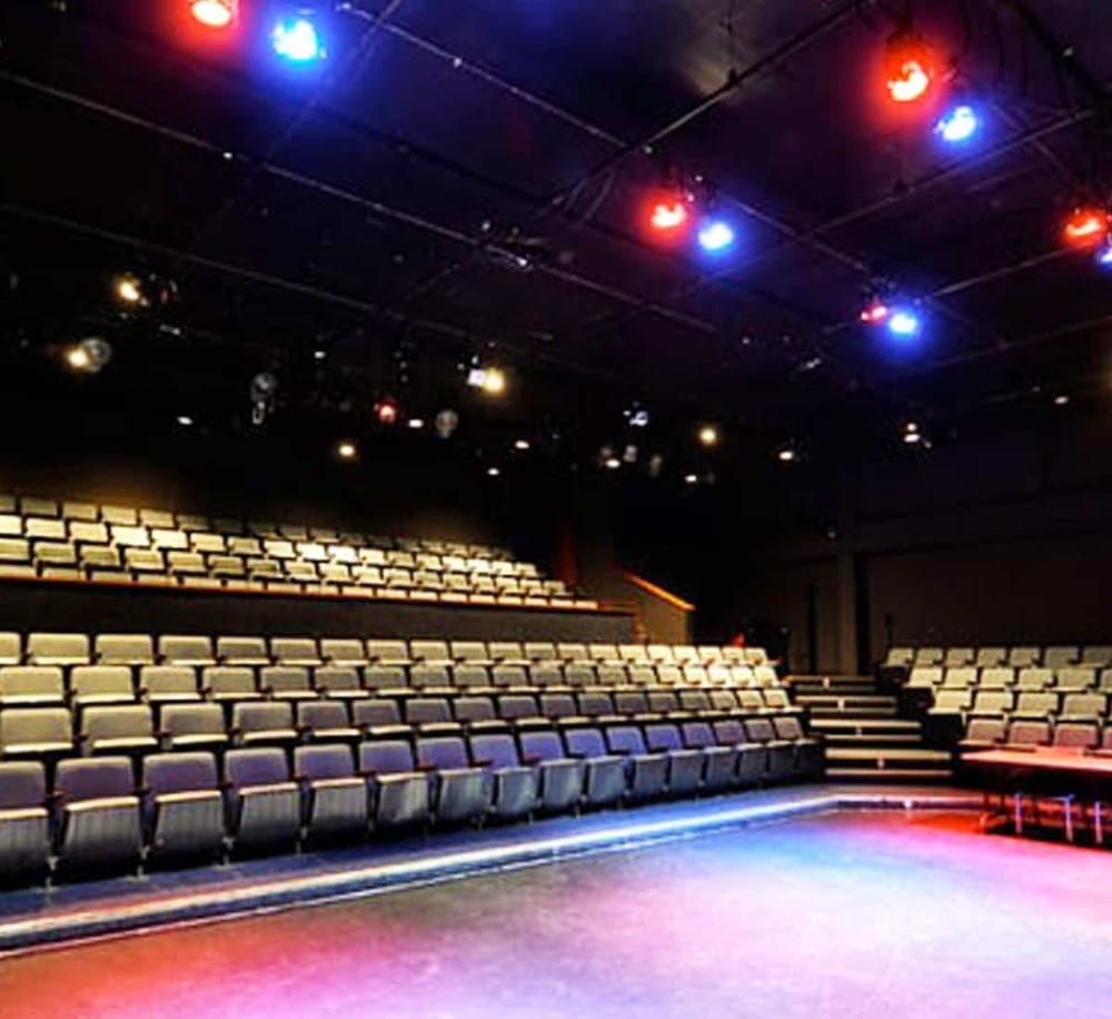 Empty theater seating with colorful stage lights, perfect for live performances and events.