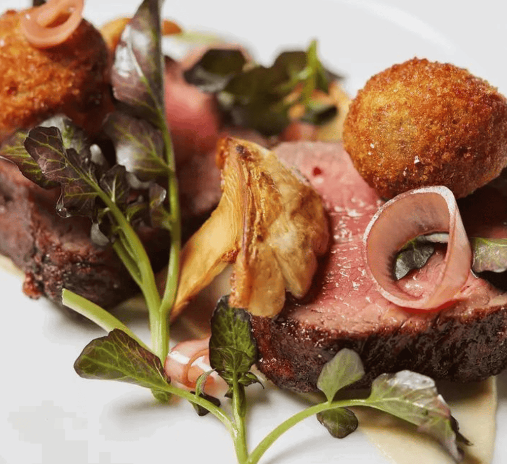 Succulent beef steak with roasted potatoes, fried croquettes, and fresh greens. Perfect gourmet dish for food lovers.