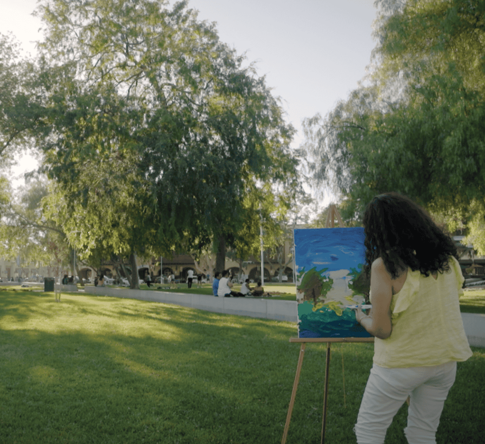 Vibrant park scene with artist painting landscape outdoors, emphasizing nature and community engagement.