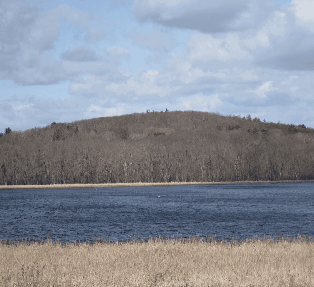 Serene lake with wooded hills, perfect for outdoor adventures and exploring nature trails.