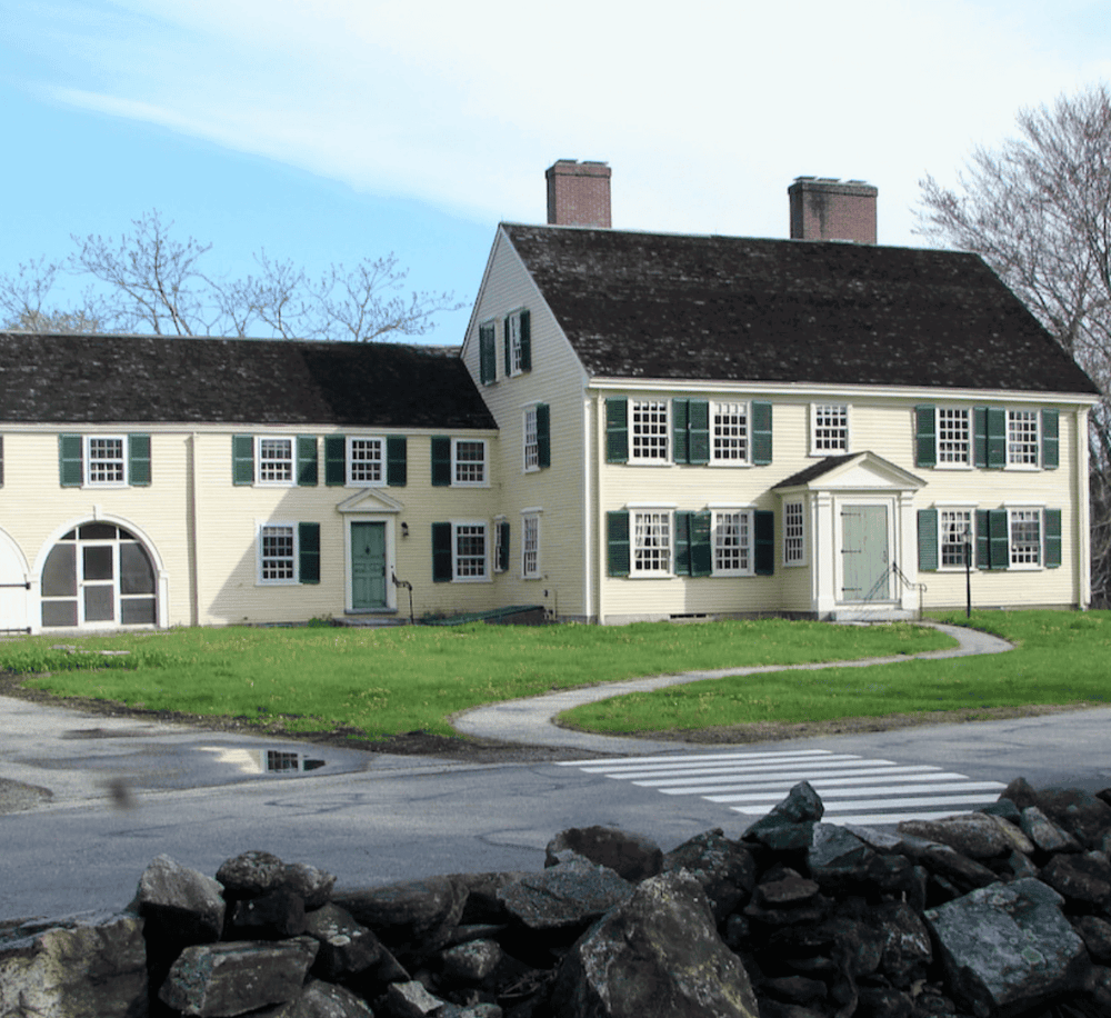 Coastal Historic House with Green Shutters, residential architecture, surrounded by rocks and greenery.