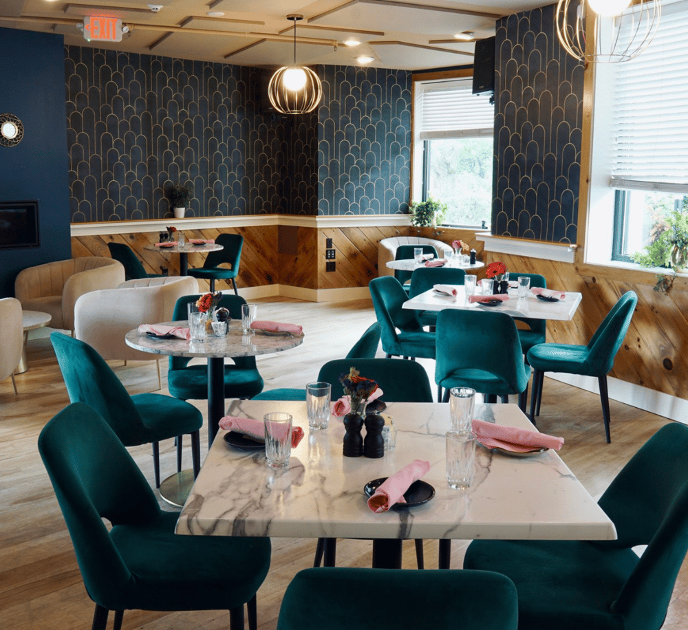 Cozy modern restaurant interior with elegant teal and beige seating, marble tables, and stylish decor.