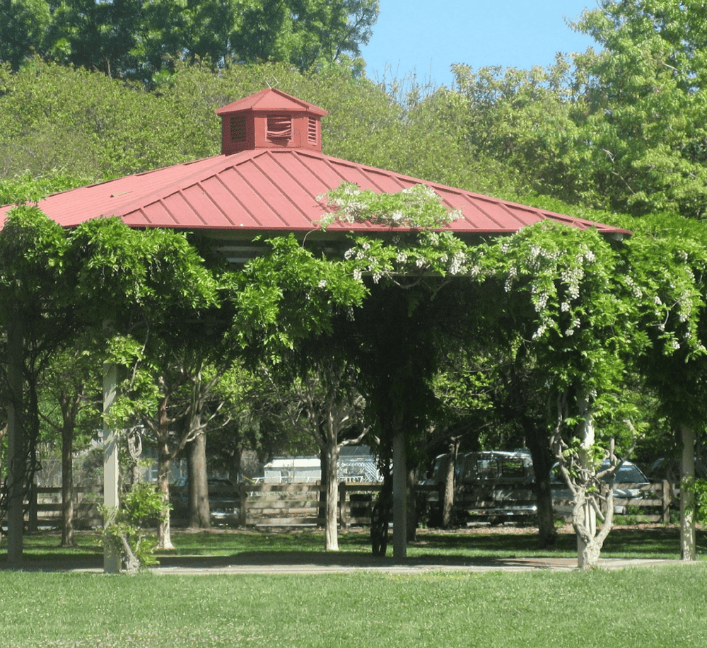 1. Gazebo with red roof surrounded by lush green trees and garden.