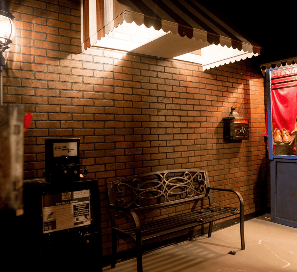 Cozy brick-walled waiting area with bench and vintage mailbox outside a store or restaurant.