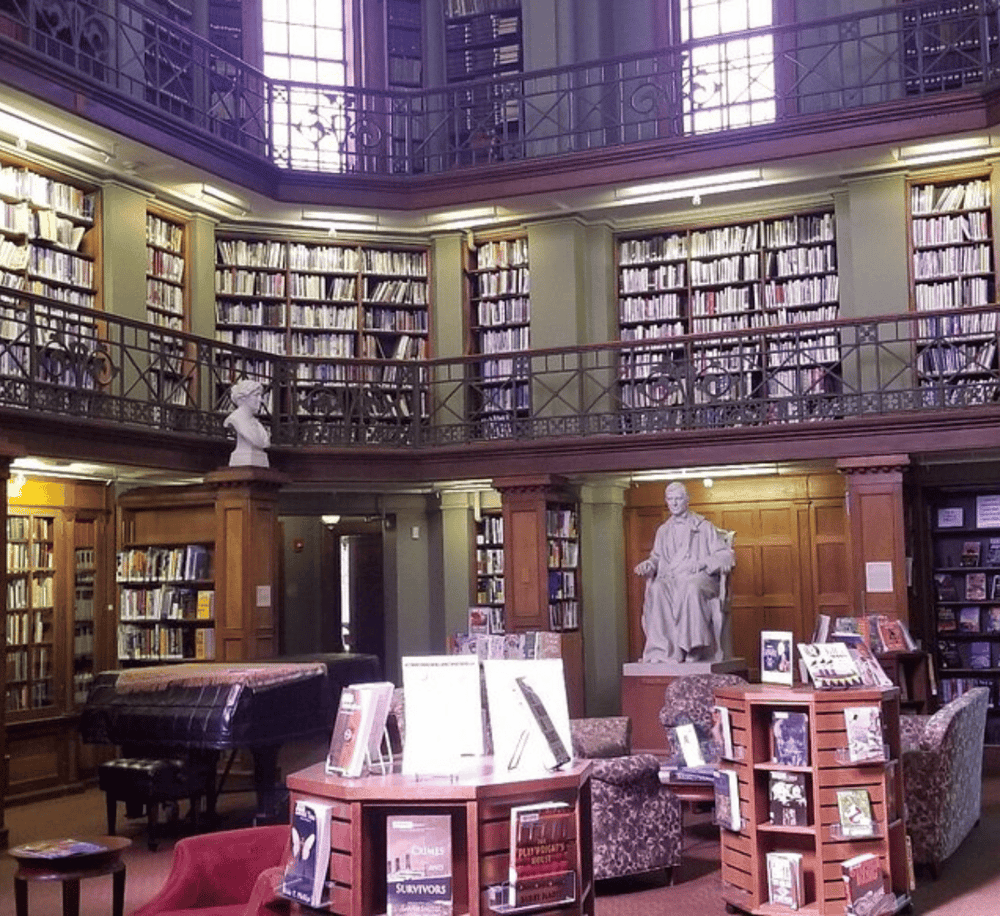 Aisle library with bookshelves and sculptures, cozy reading space in a historic library setting.