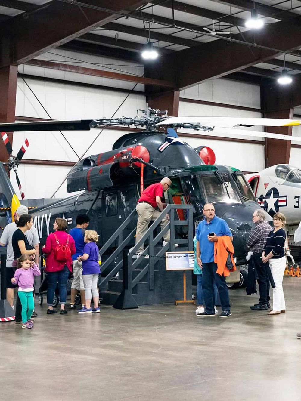 Military helicopter exhibit at the museum with visitors exploring and learning.