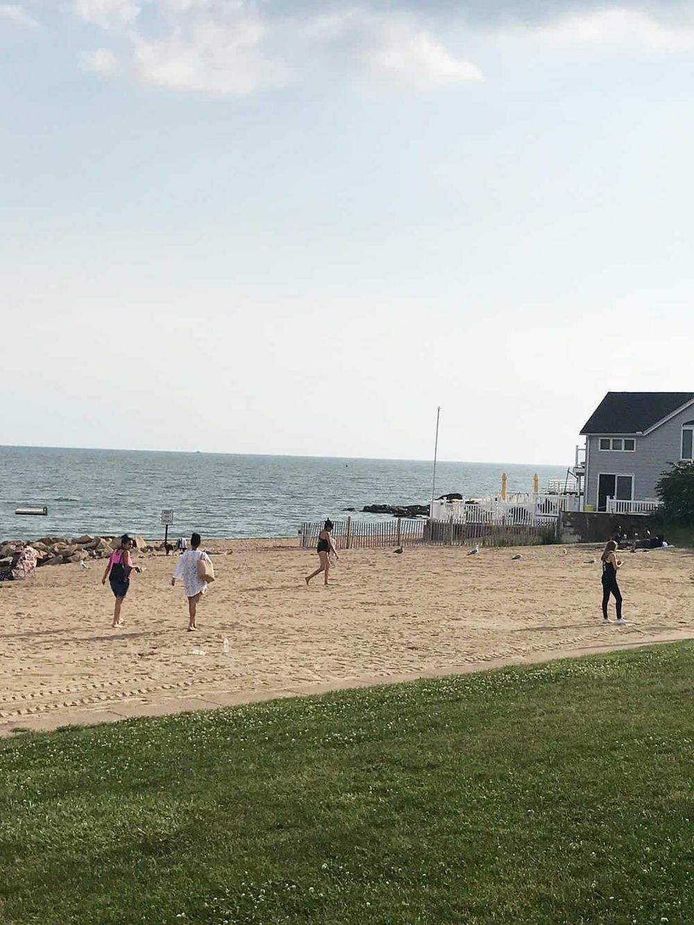 People walking on sandy beach with ocean view in the background.