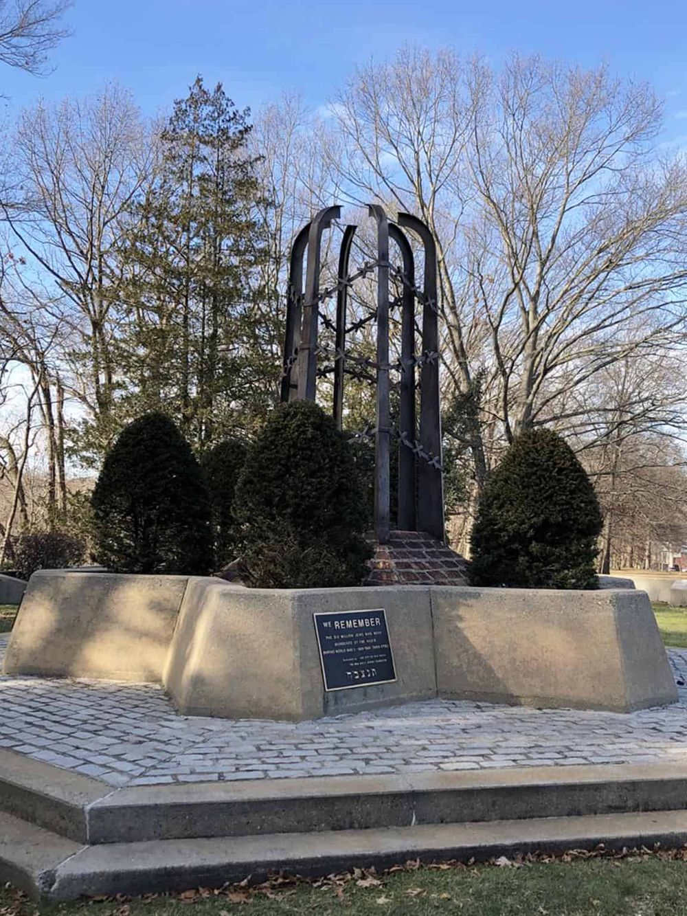 Remembrance monument with metal and stone design in a park setting, honoring fallen heroes.