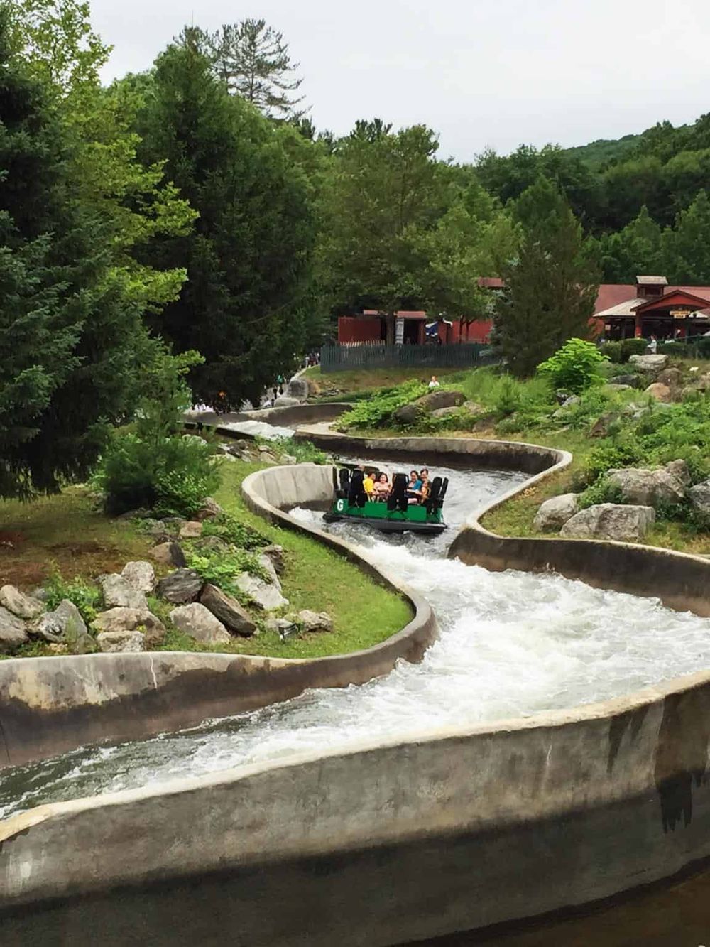 Thrilling water ride at Quest for Directions amusement park with lush green trees in the background.