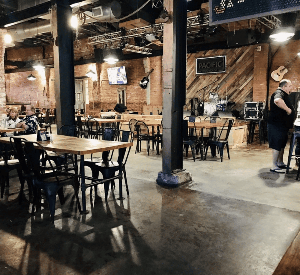 Live music venue at Quest For Directions with stage, musical instruments, and cozy industrial decor.