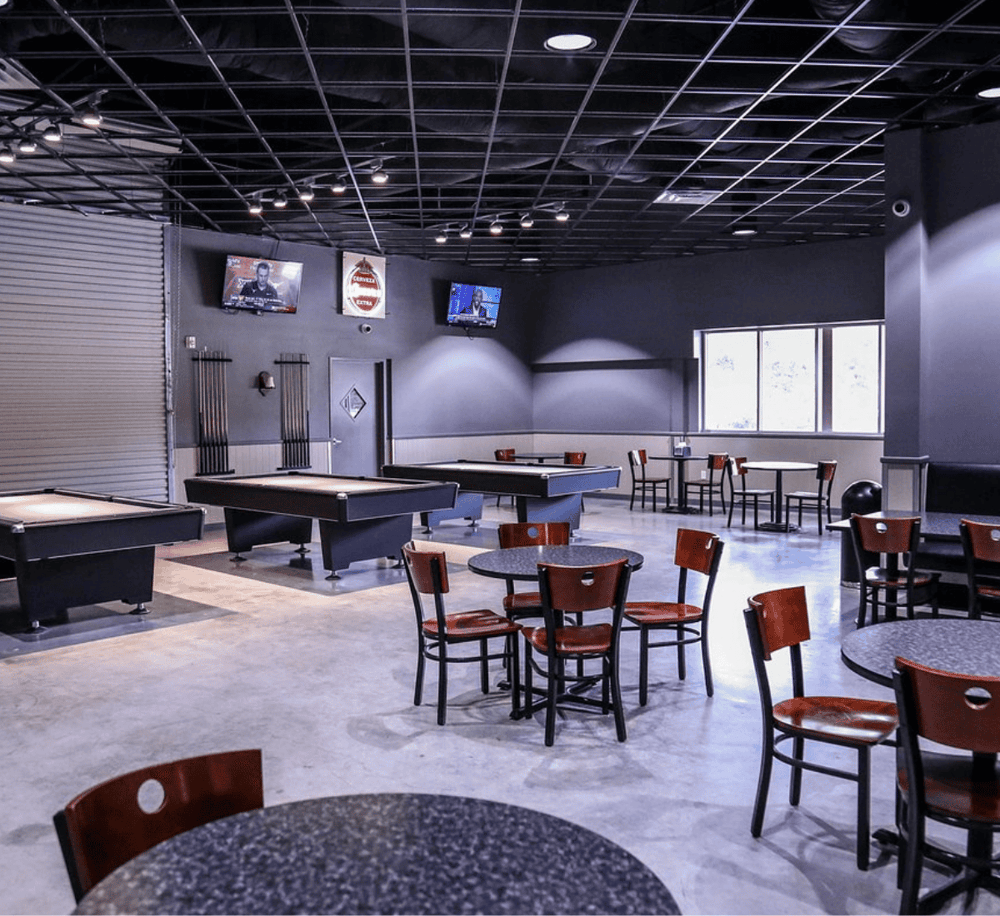 Modern indoor sports bar with pool tables, TVs, and casual seating for sports fans.