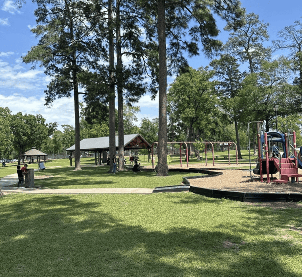 Children playing in a park with playground and picnic shelters, perfect for family outings and outdoor recreation.