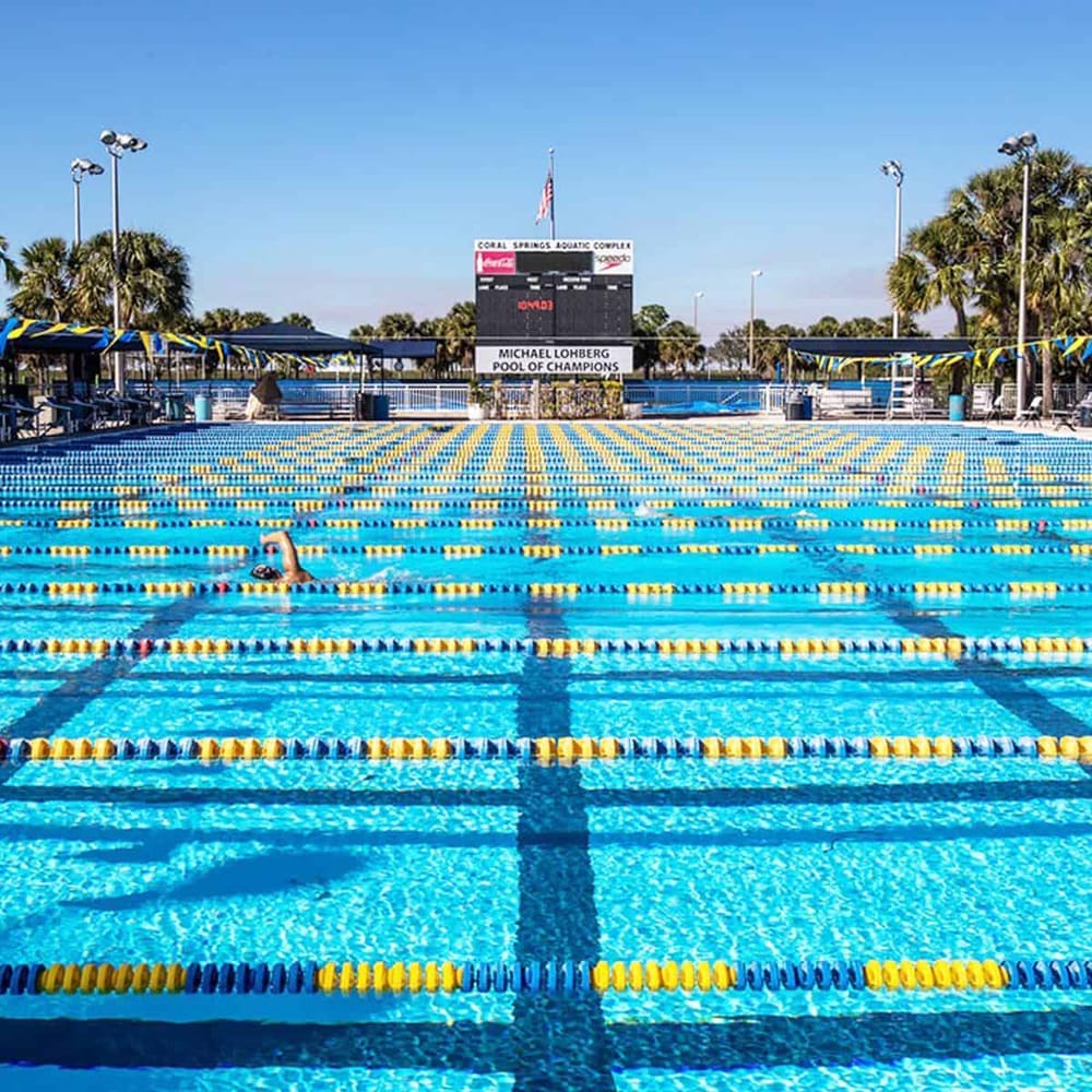 Outdoor swimming pool at Coral Springs Aquatic Complex with lane markers and swimmer.