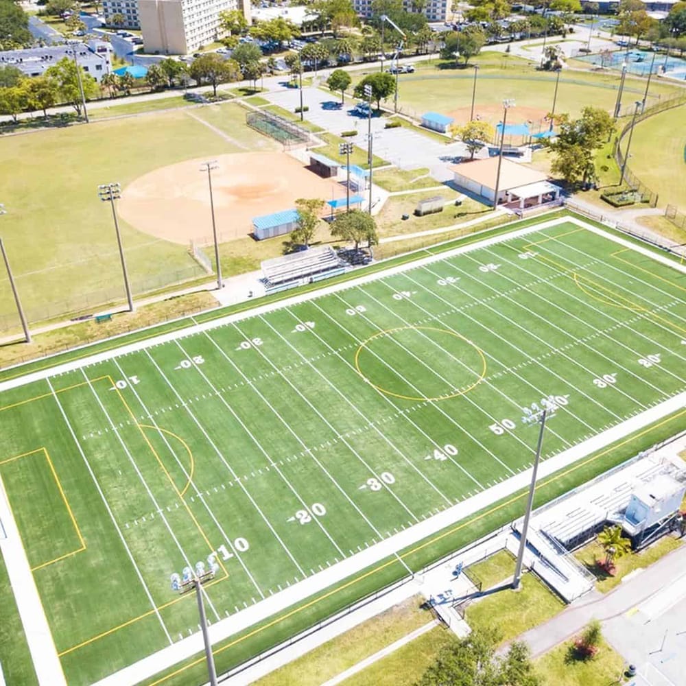 Bright aerial view of a professional football field and surrounding sports facilities at QuestForDirections.