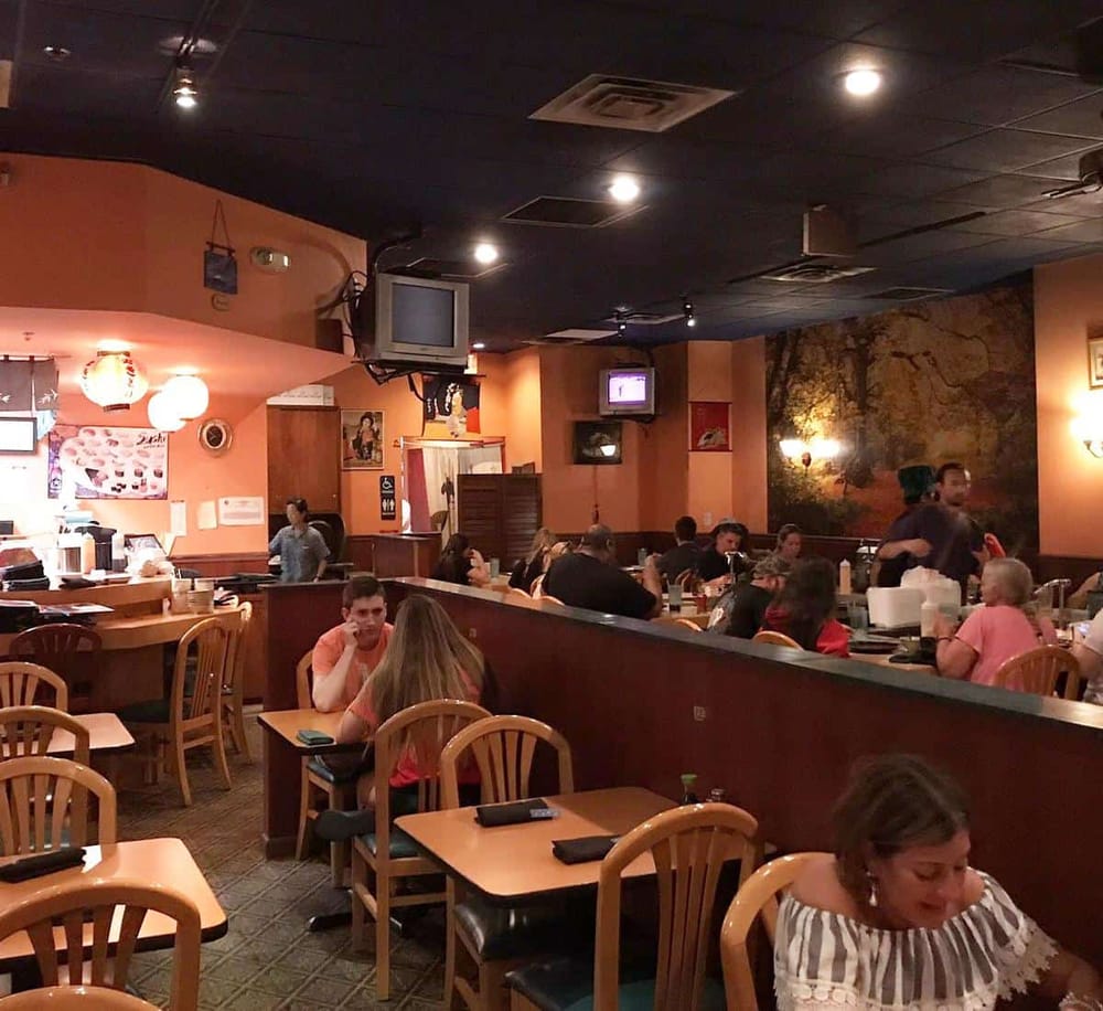 Cozy Asian restaurant interior with warm lighting, diners enjoying meals, and traditional decor.