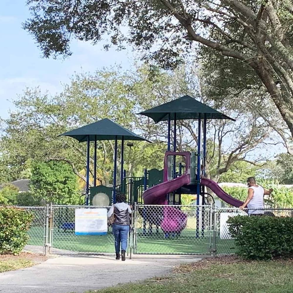 Colorful playground slide at a public park with trees and fence, perfect for kids' outdoor activities.