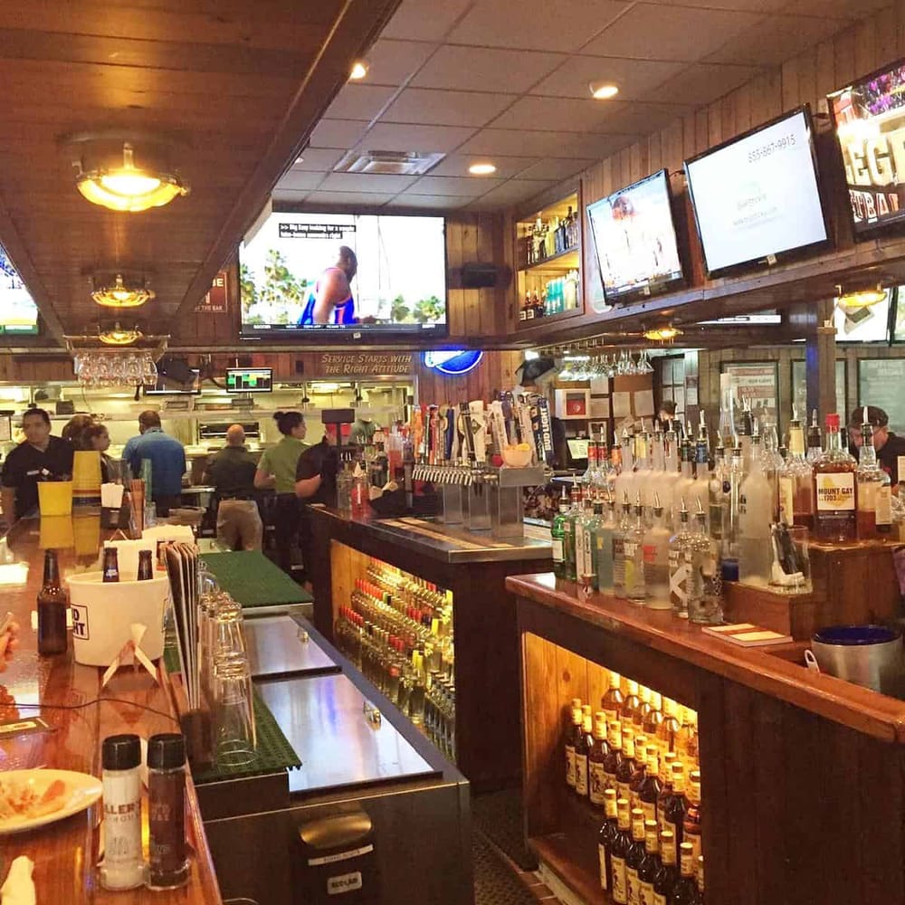 Beer bar with multiple screens at QuestForDirections, lively atmosphere, and wood-paneled decor.