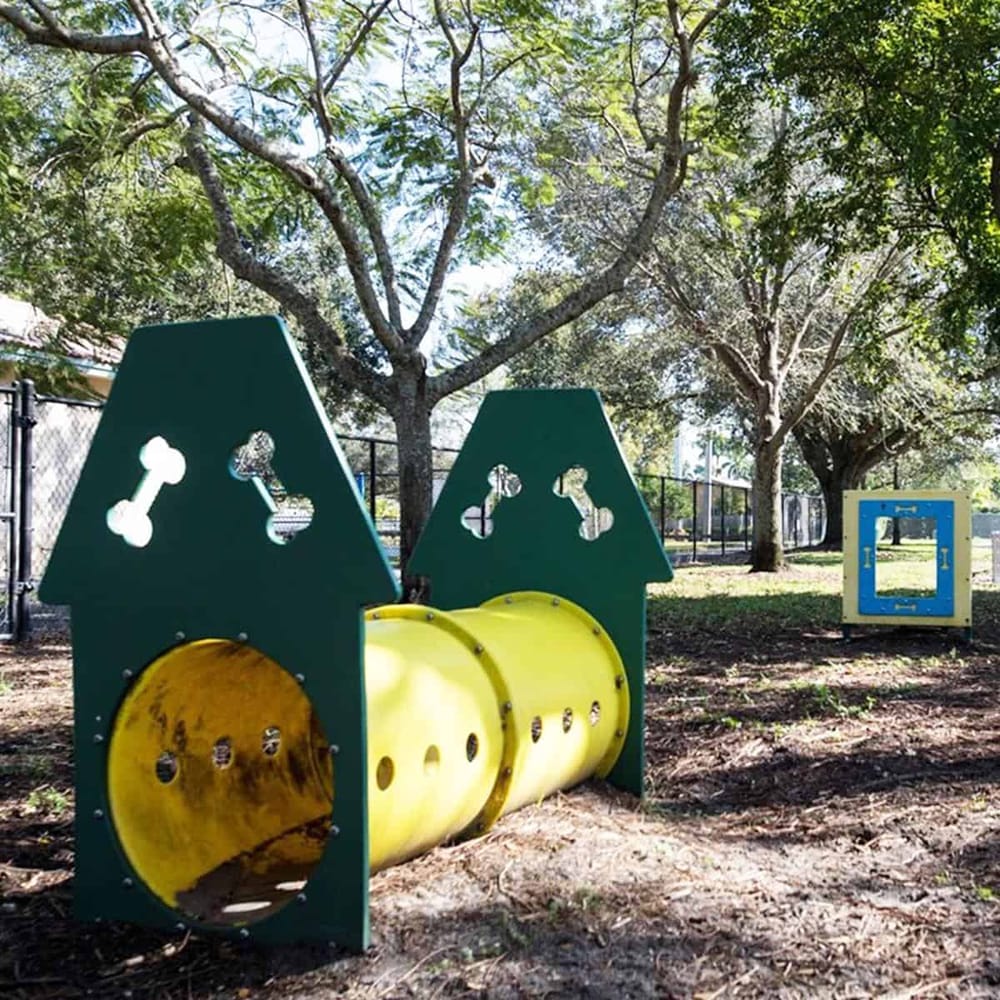 Colorful playground tunnel with dog bone cutouts in a park setting.