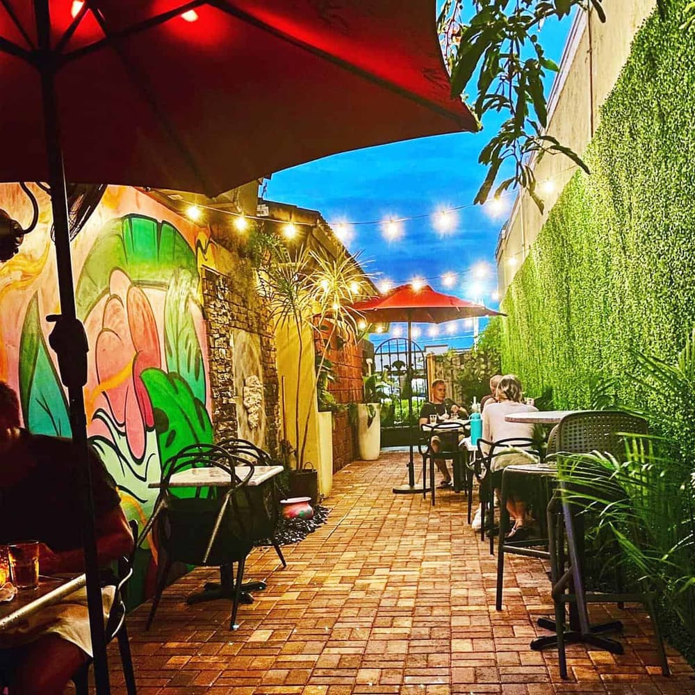 Colorful outdoor patio with string lights, lush greenery, and vibrant wall art at QuestForDirections restaurant.