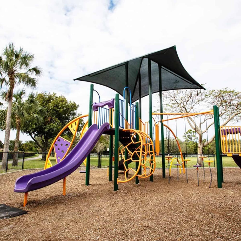 Colorful outdoor playground equipment with slide, climbing structures, and shade, ideal for children's recreation.