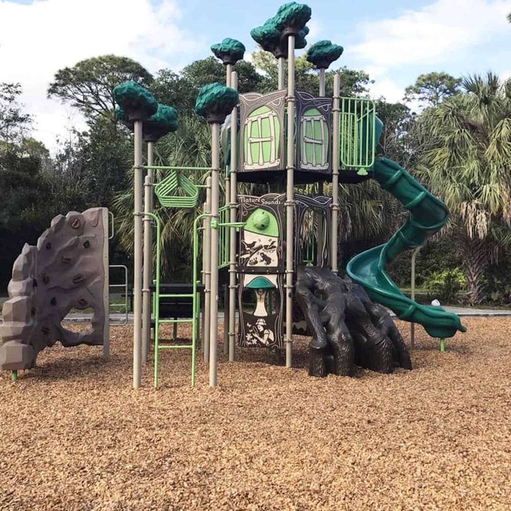 Colorful children's playground with slides and climbing structures in a park setting.