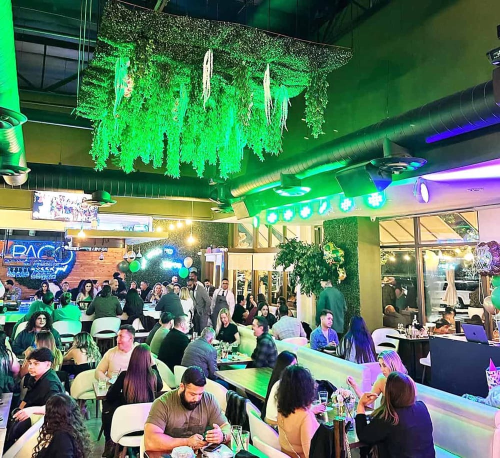 Vibrant indoor restaurant with lush green ceiling decor and colorful lighting, perfect for social dining experiences.