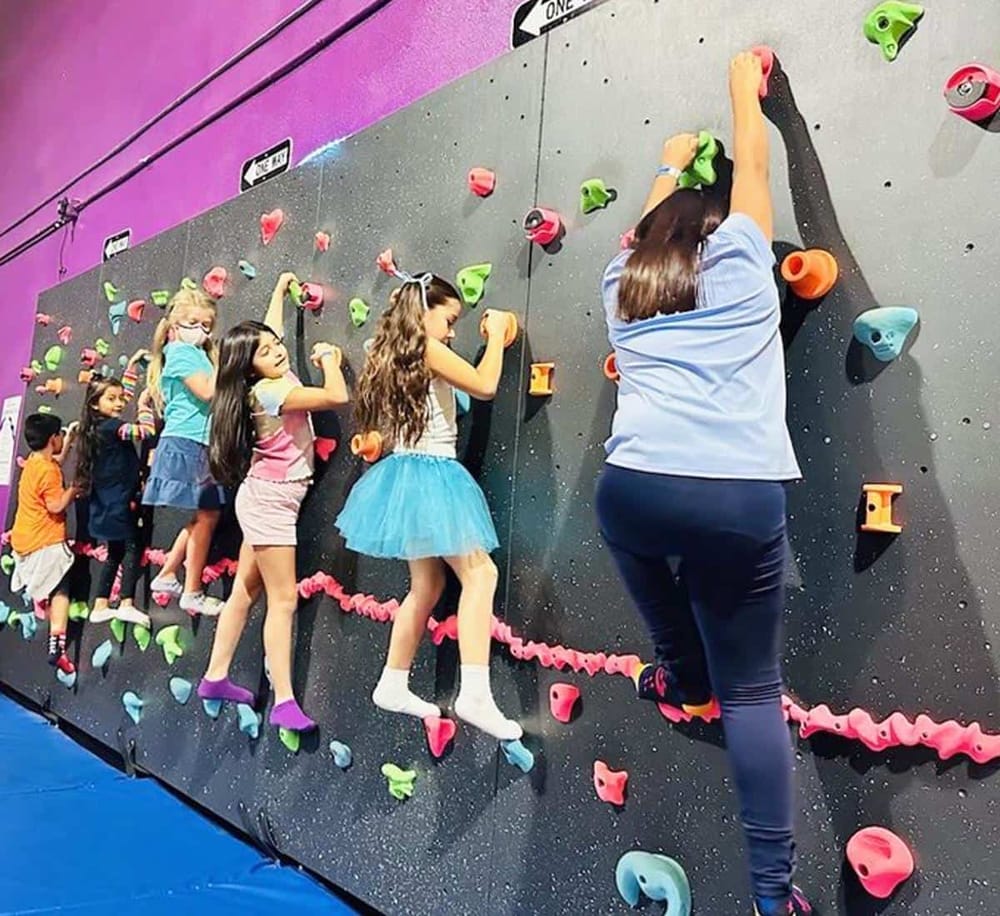Kids enjoying indoor rock climbing at QuestForDirections climbing gym. Fun activities for children and families.