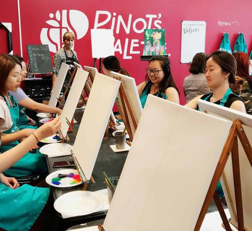 Colorful painting class at Pinot's Palette studio. Happy participants sipping paint in a vibrant art workshop.