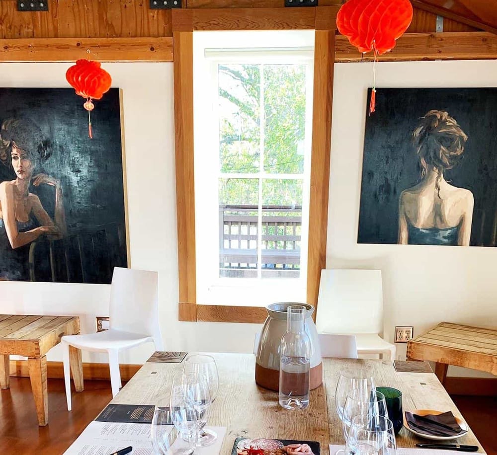 Relaxing dining room with large window, modern artwork, and cozy rustic decor for an inviting ambiance.