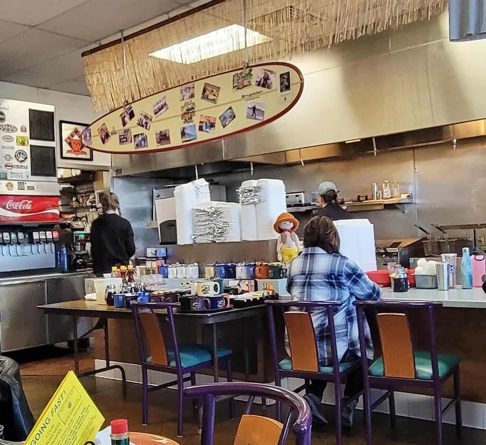 1. Cozy diner interior with customers and staff, casual atmosphere, and travel-themed decor.