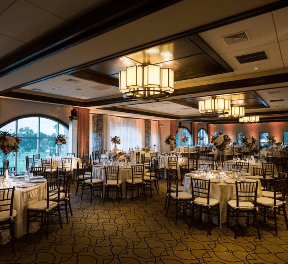Elegant banquet hall with round tables, floral centerpieces, and ambient lighting for special events.