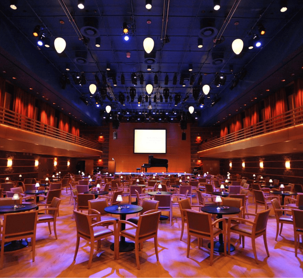 Bright, modern event venue with stage, seating, and professional lighting for performances and conferences.