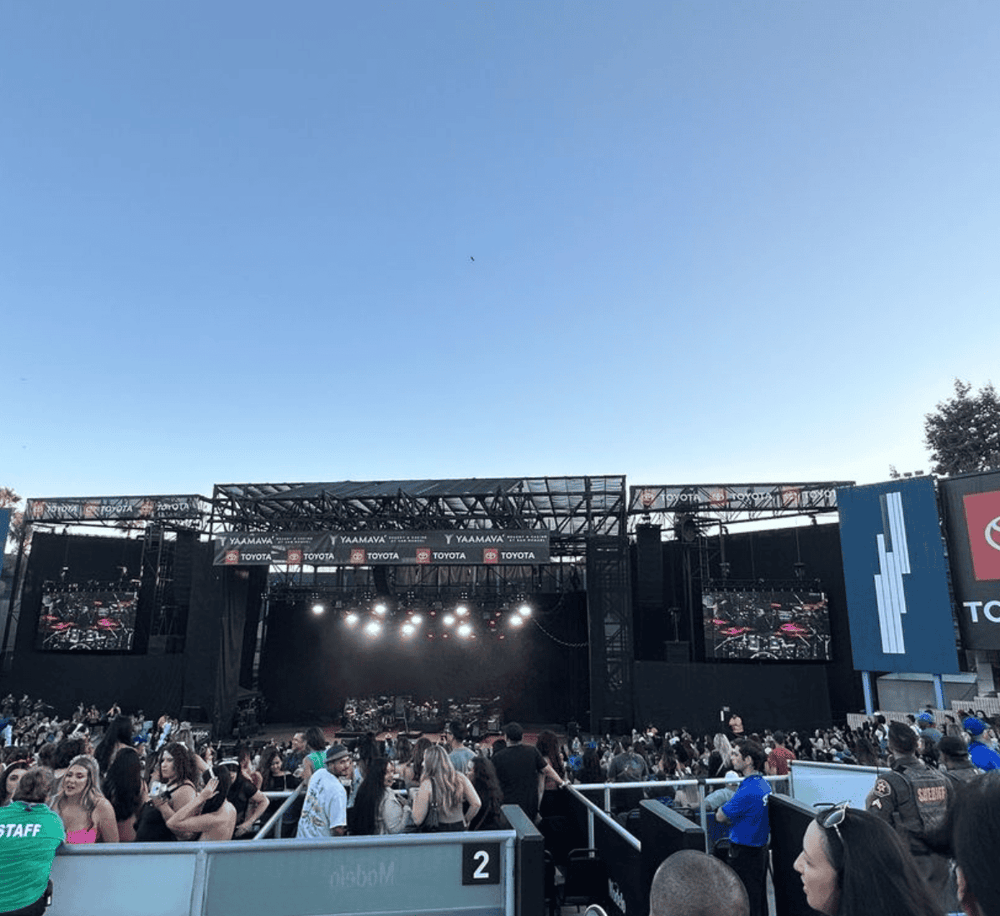 1. Large outdoor concert stage with crowd, under clear blue sky, at a music festival.