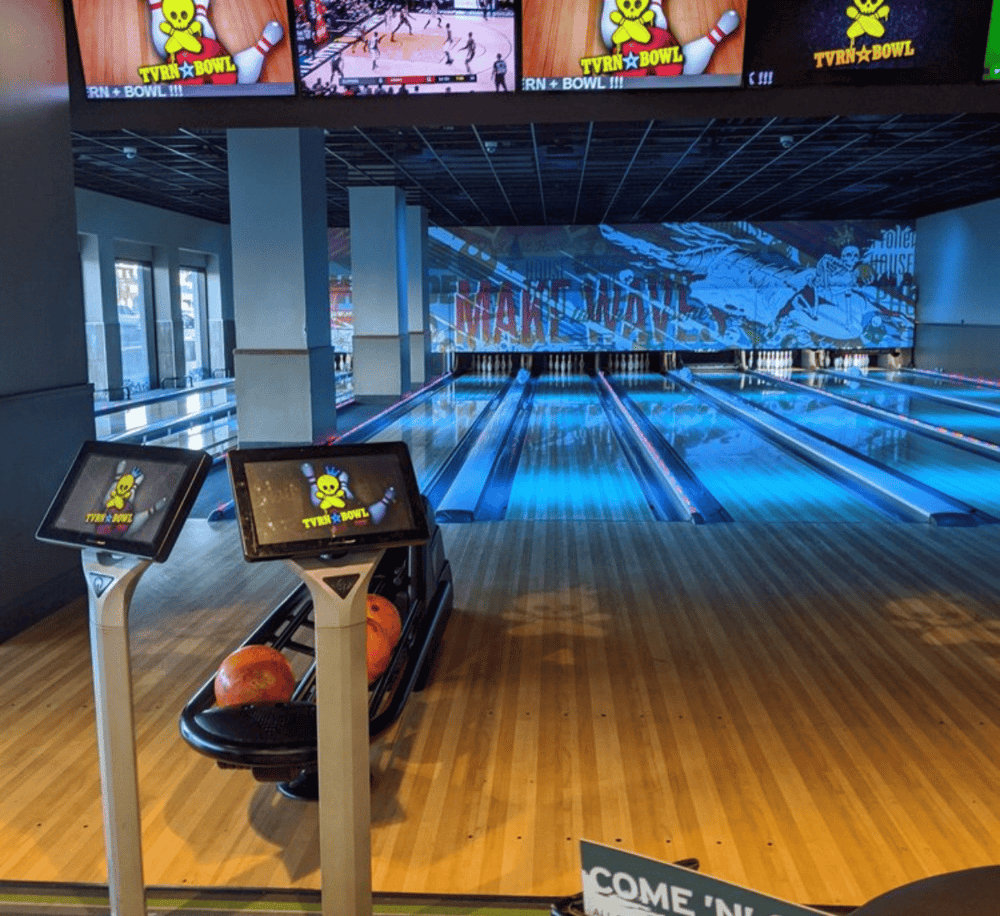 Bowling alley at QuestForDirections with digital screens and vibrant decor.
