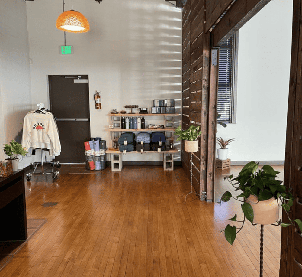 Cozy boutique retail space with wooden floors and potted plants for sale or display.