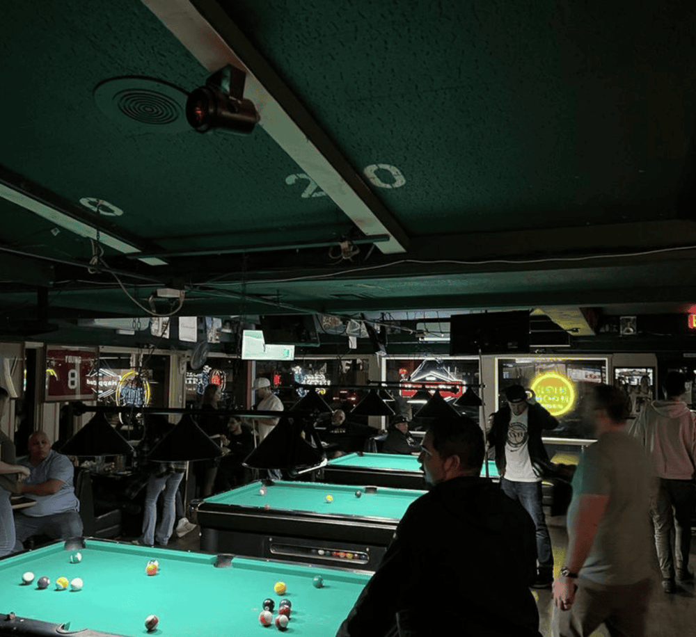 Relaxing pool hall with multiple billiard tables and players enjoying a game.