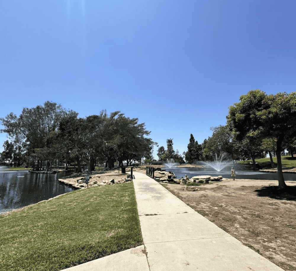 Tranquil park with walking path, water fountains, and lush trees, perfect for outdoor recreation and relaxation.