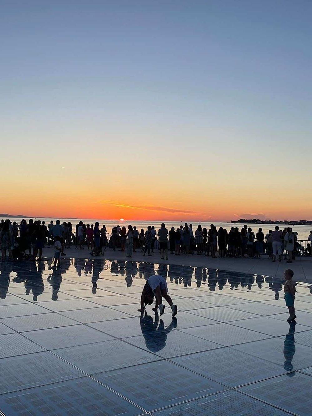 Dusk at QuestForDirections outdoor plaza with silhouettes and a vibrant sunset sky.
