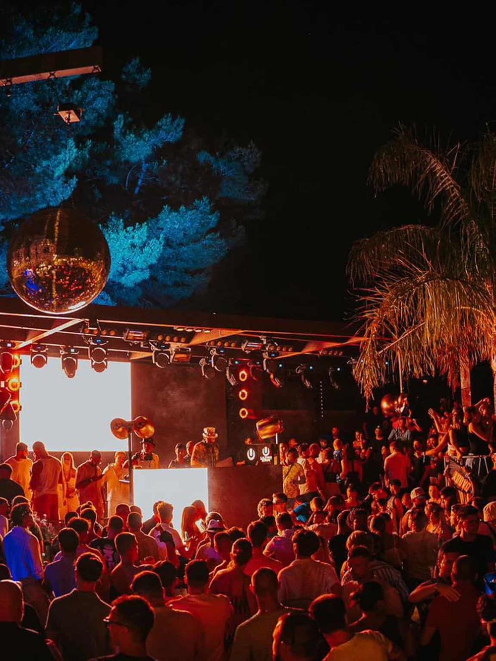 Outdoor nighttime event at a music festival with vibrant lighting and a large crowd.