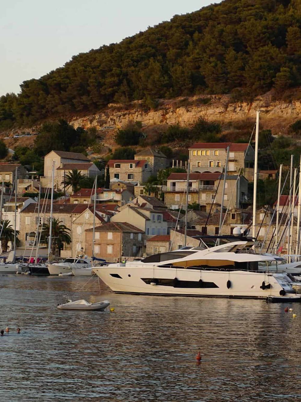Luxurious yacht docked in a scenic harbor with hillside town, perfect for travel navigation insights.