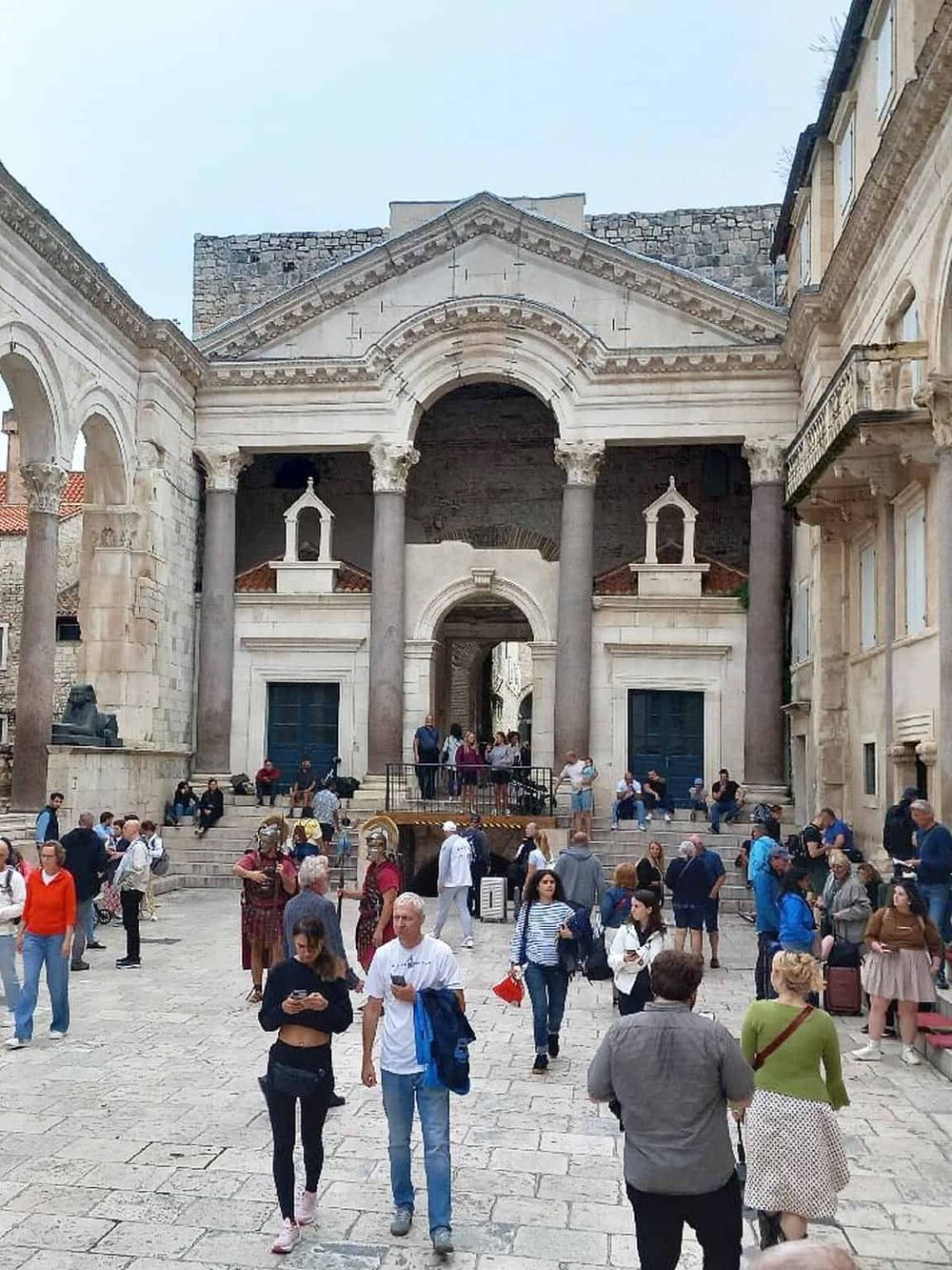 1. Historic ruins with stone architecture and crowd in a busy city square.