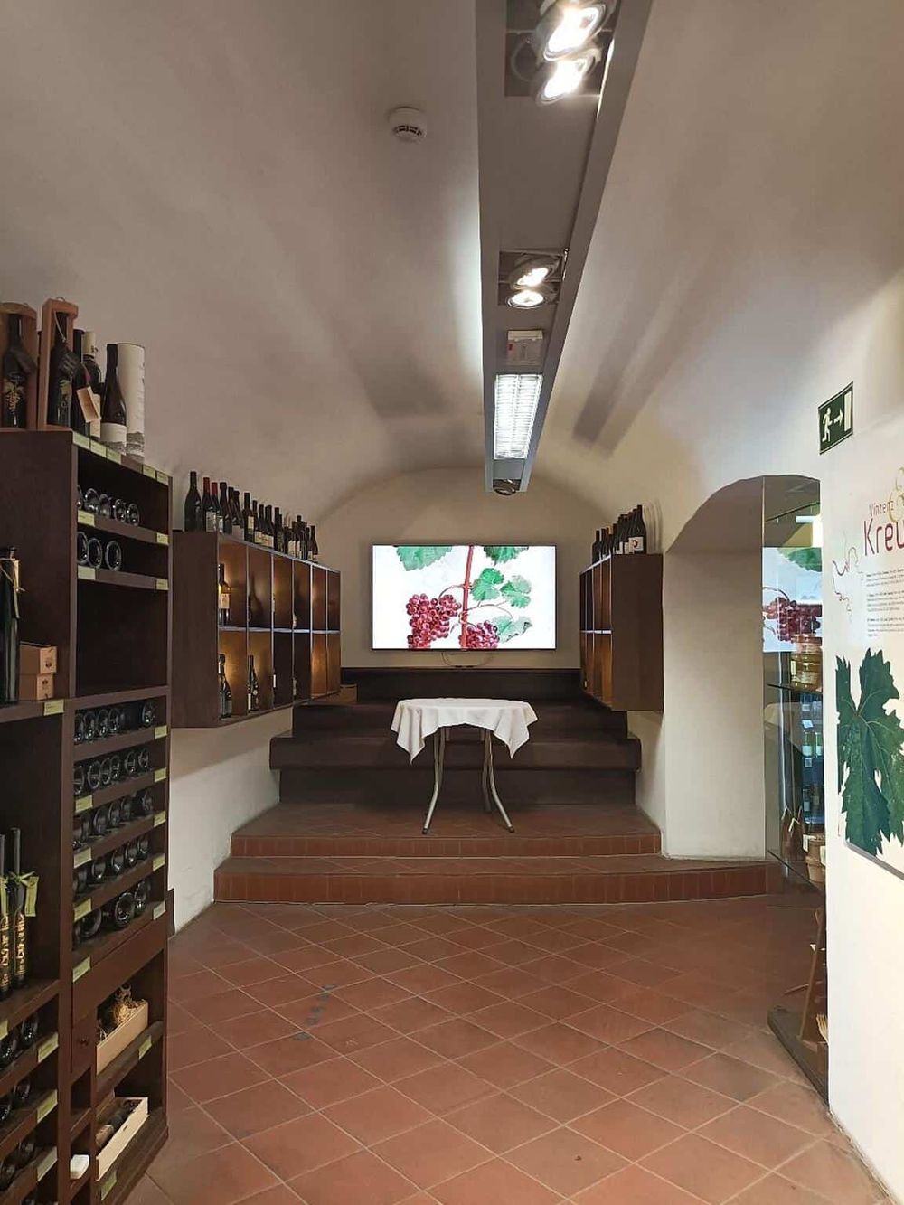Cozy wine tasting room with wine bottles, a digital display, and comfortable seating for tasting experience.