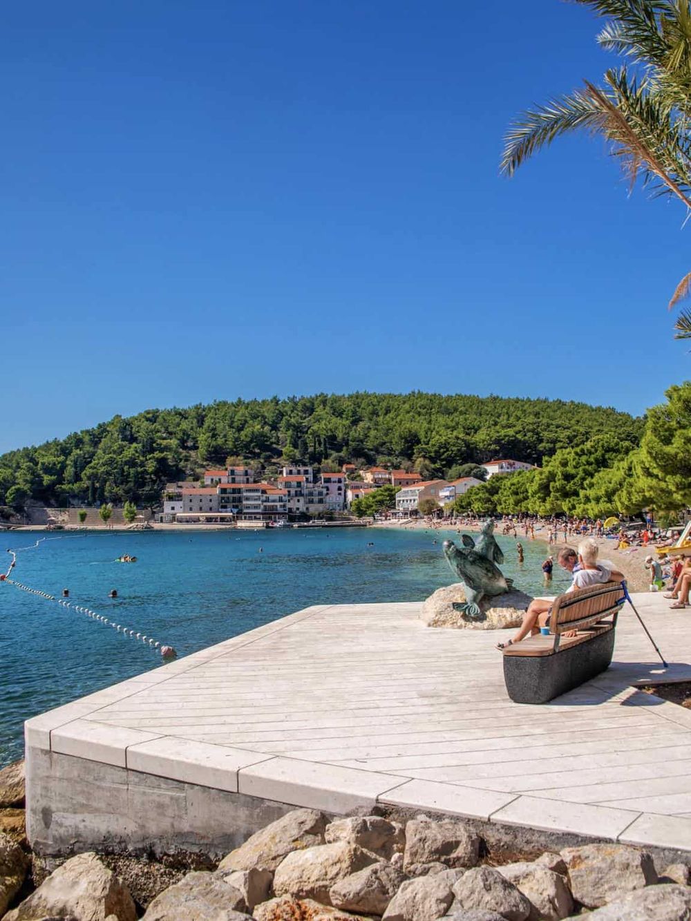 Relaxing seaside town with clear waters, sandy beaches, and lush green hills, perfect for travel and vacation planning.