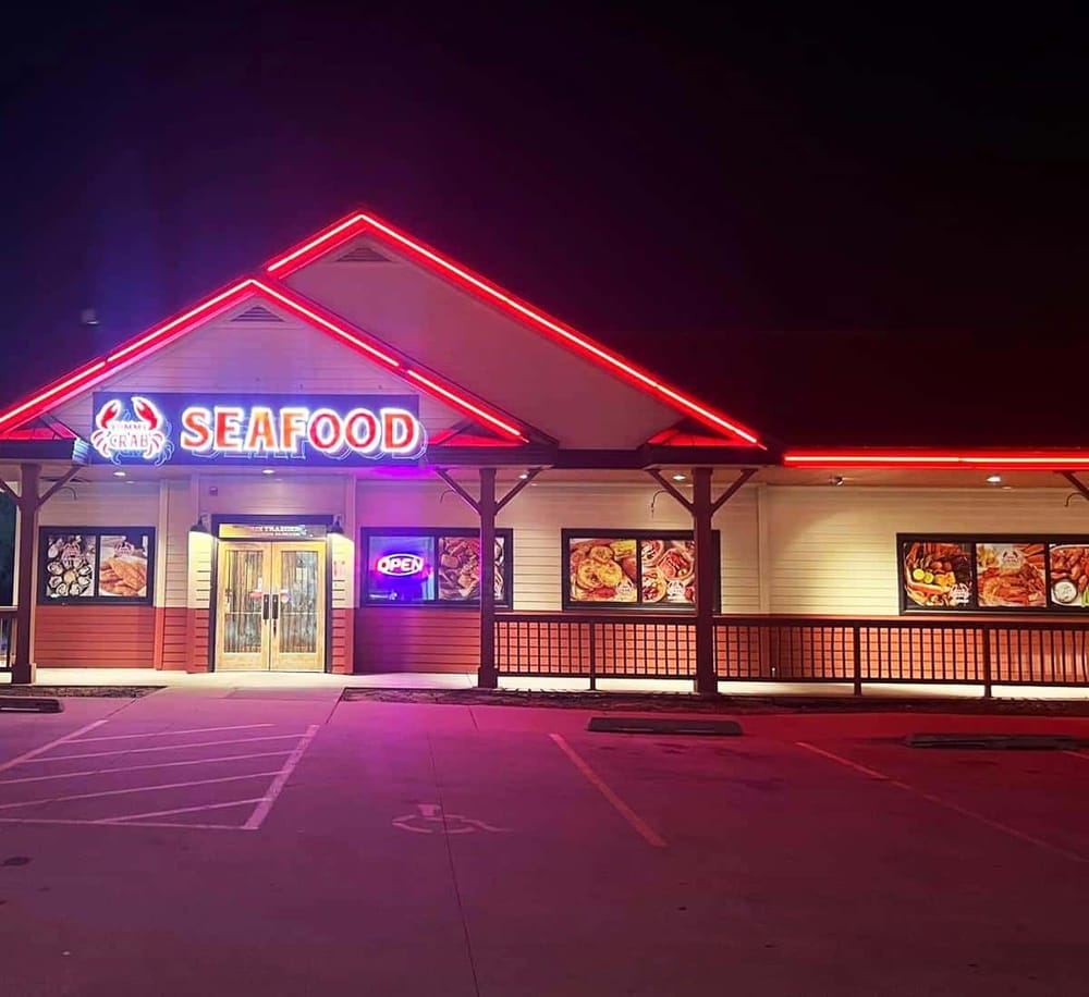 Neon-lit seafood restaurant exterior at night with a prominent "Seafood" sign and illuminated menu images.