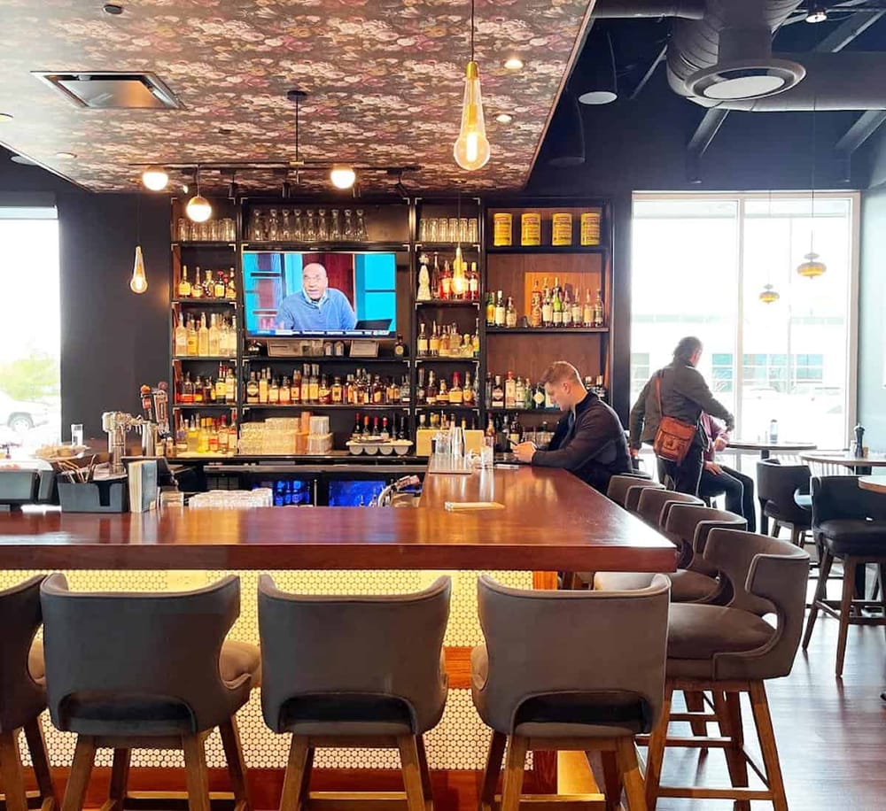 Modern bar interior with whiskey bottles and a flat-screen TV, inviting atmosphere for socializing.