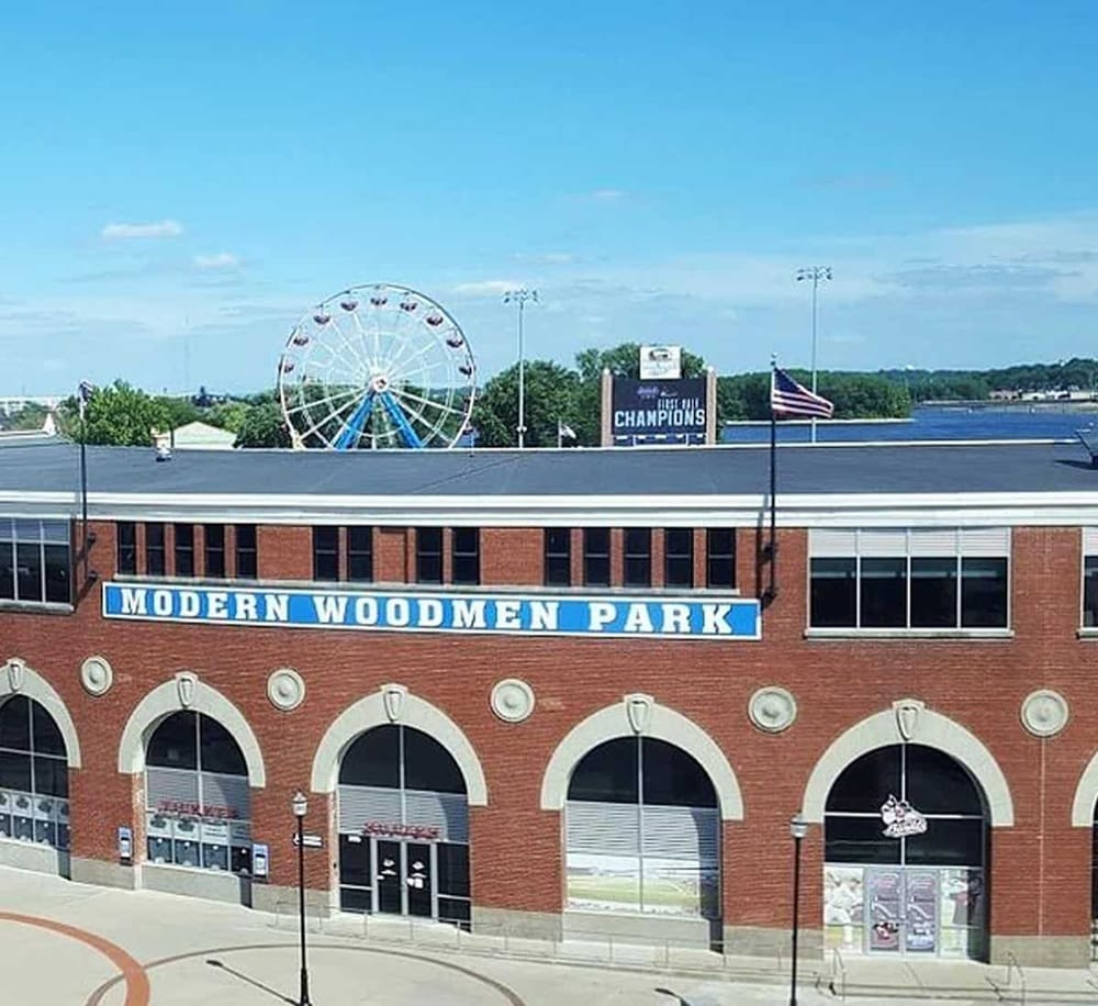 Ferris wheel at Modern Woodmen Park in Davenport Iowa with river views and sports scoreboard in background.