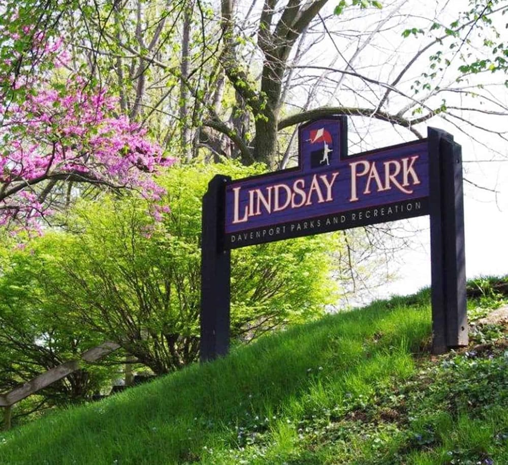 Lindsay Park sign surrounded by blooming trees and lush greenery in Davenport, perfect for outdoor recreation.