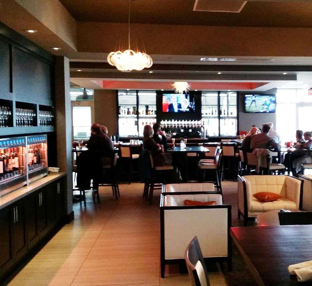 Comfortable sports bar with multiple TVs, bar seating, and modern decor, perfect for watching games and enjoying drinks.