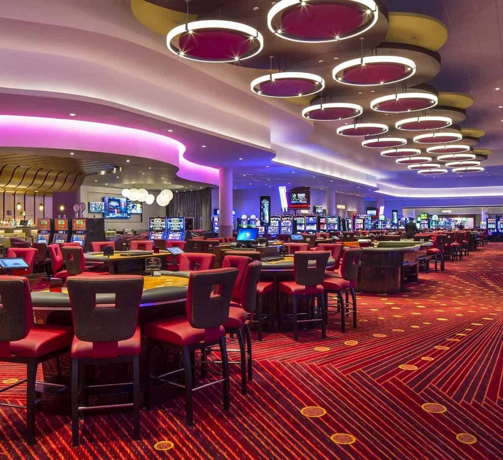 Bright casino gaming area with slot machines, modern lighting, and vibrant carpet design.